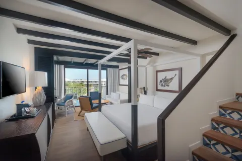 Loft-style guest room with king bed, stairs, and balcony at Ocean Riviera Paradise.