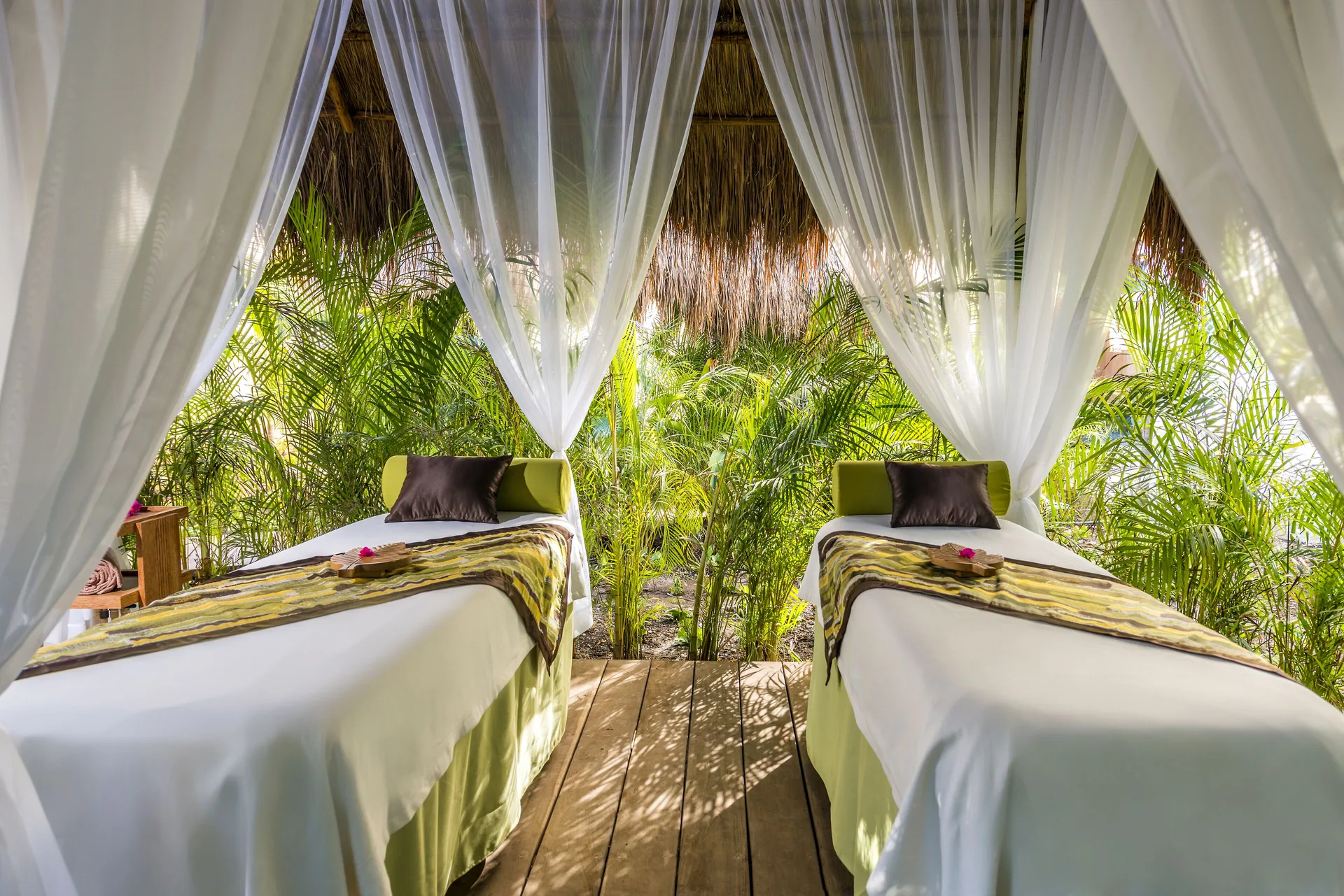 Outdoor spa cabana with two massage tables and sheer curtains at Ocean Riviera Paradise.