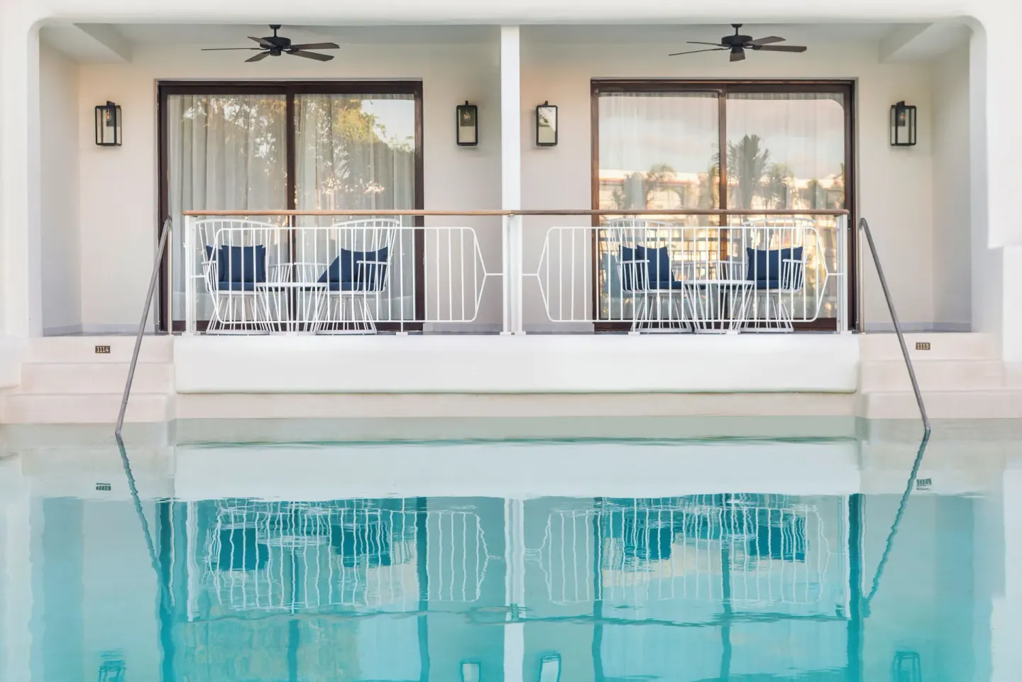 Swim-up room terraces with seating beside a pool at Ocean Riviera Paradise.