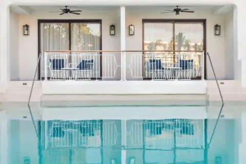 Swim-up room terraces with seating beside a pool at Ocean Riviera Paradise.
