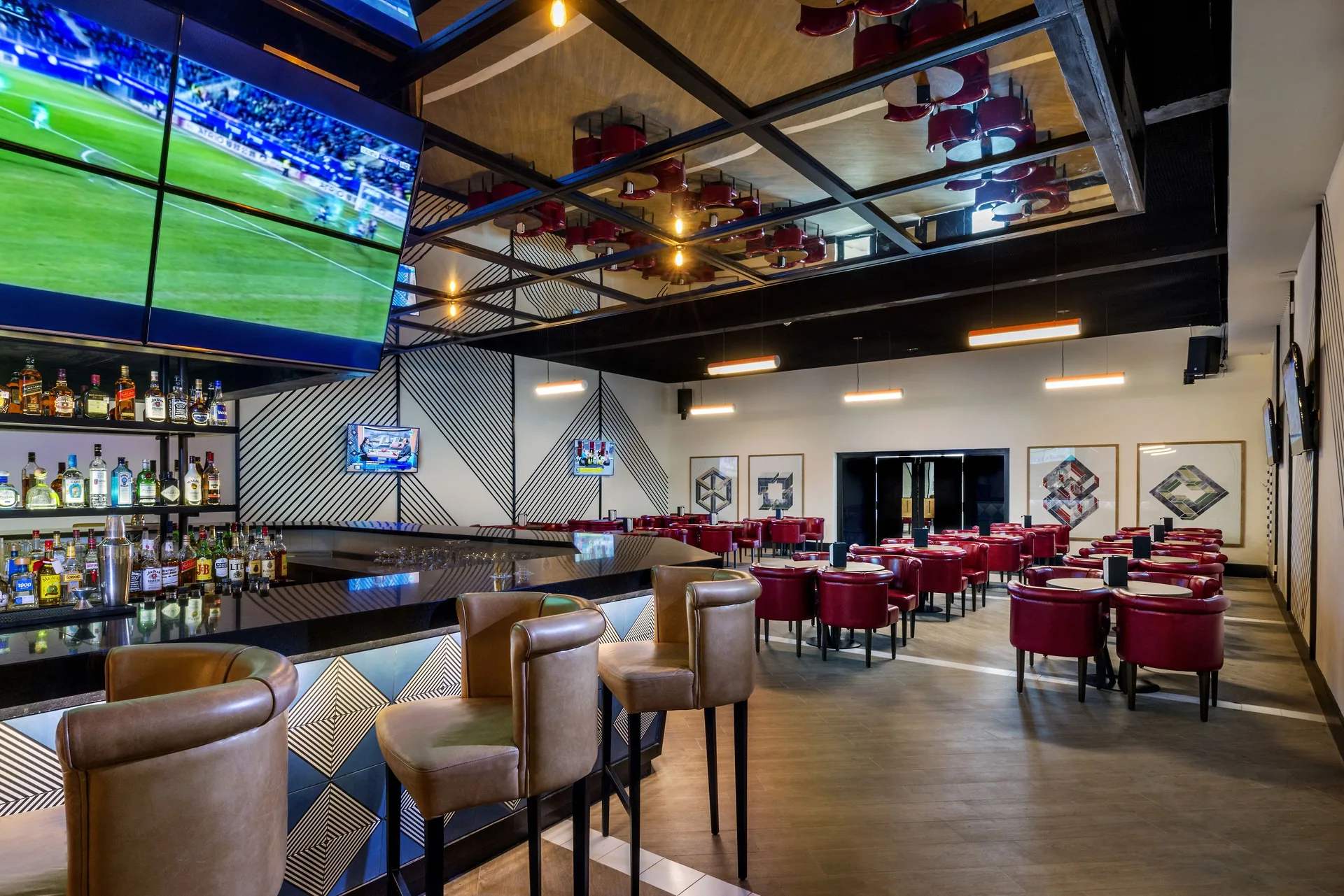 Sports bar with large TV screens and red seating at Ocean Riviera Paradise.