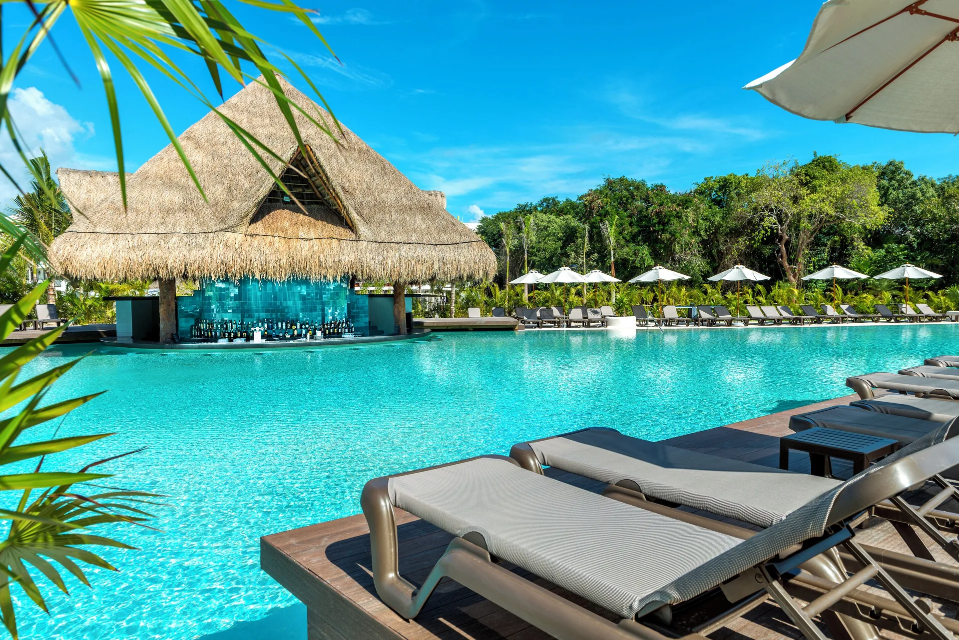 Pool with loungers and thatched swim-up bar at Ocean Riviera Paradise.