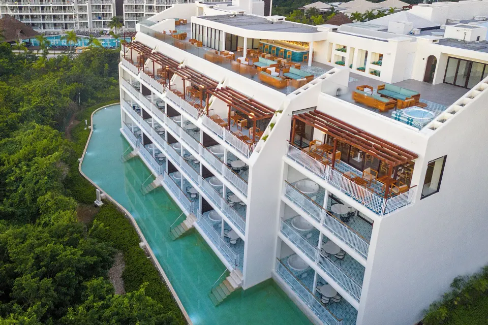 Privilege building balconies and swim-up pool by greenery at Ocean Riviera Paradise.