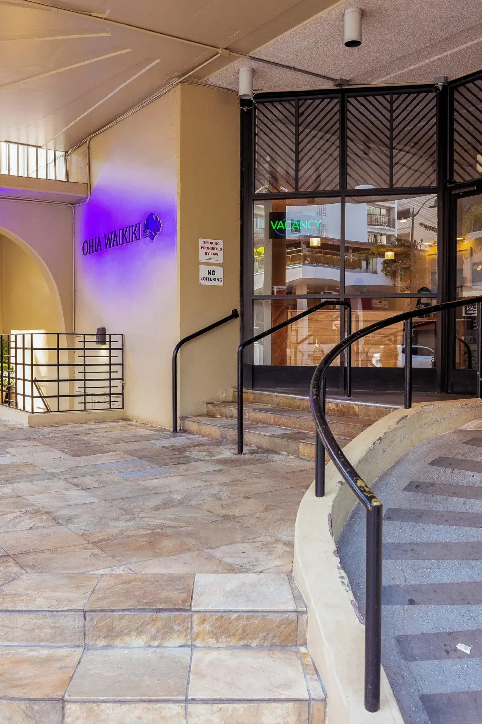 Covered entrance with glass doors and steps at Ohia Waikiki Studio Suites.