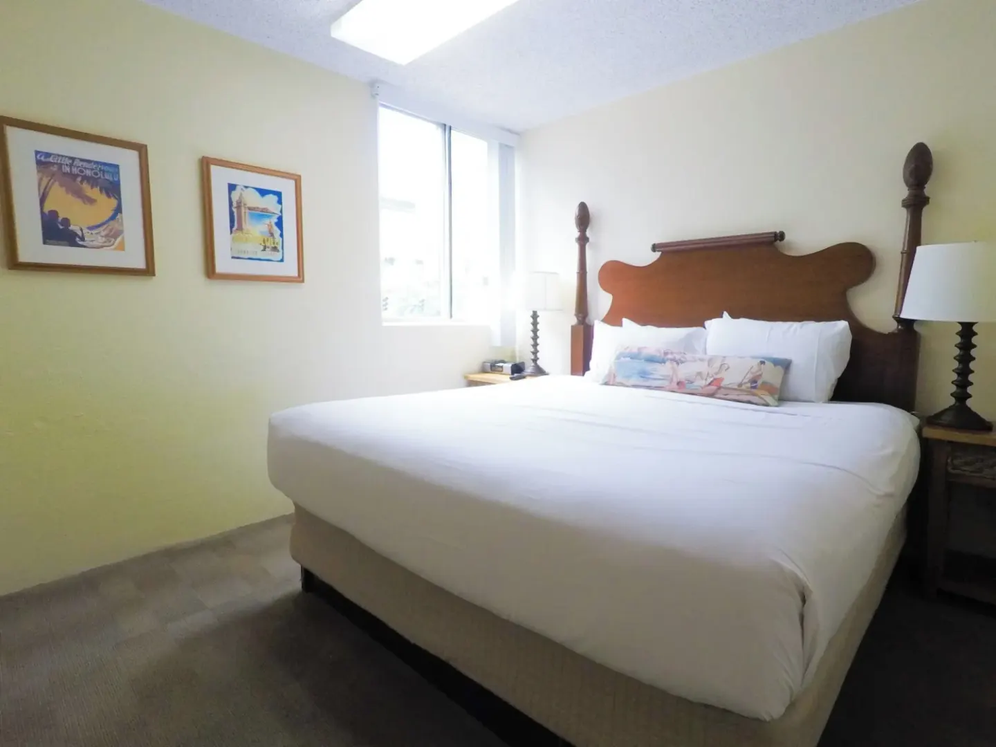 Guest room with one bed, framed wall art, and bedside lamps at Ohia Waikiki Studio Suites.