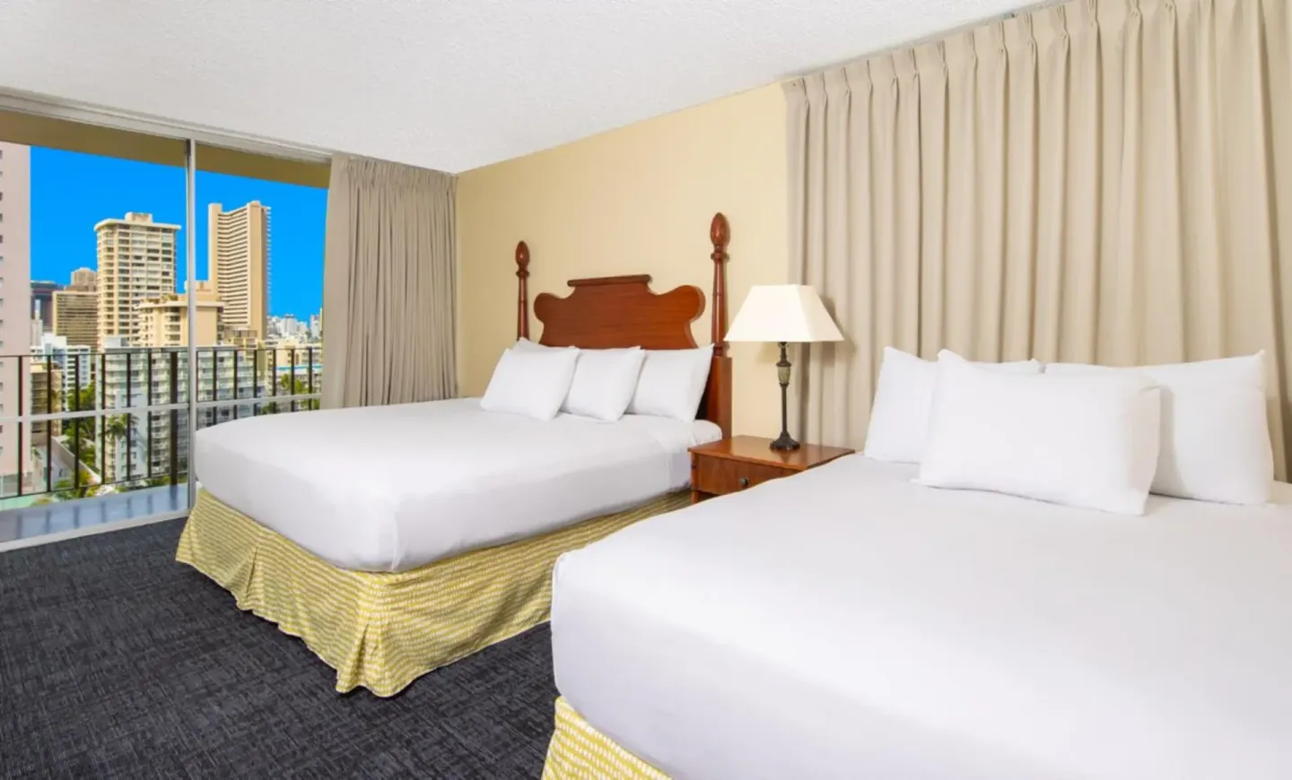 Guest room with two beds and balcony city view at Ohia Waikiki Studio Suites.