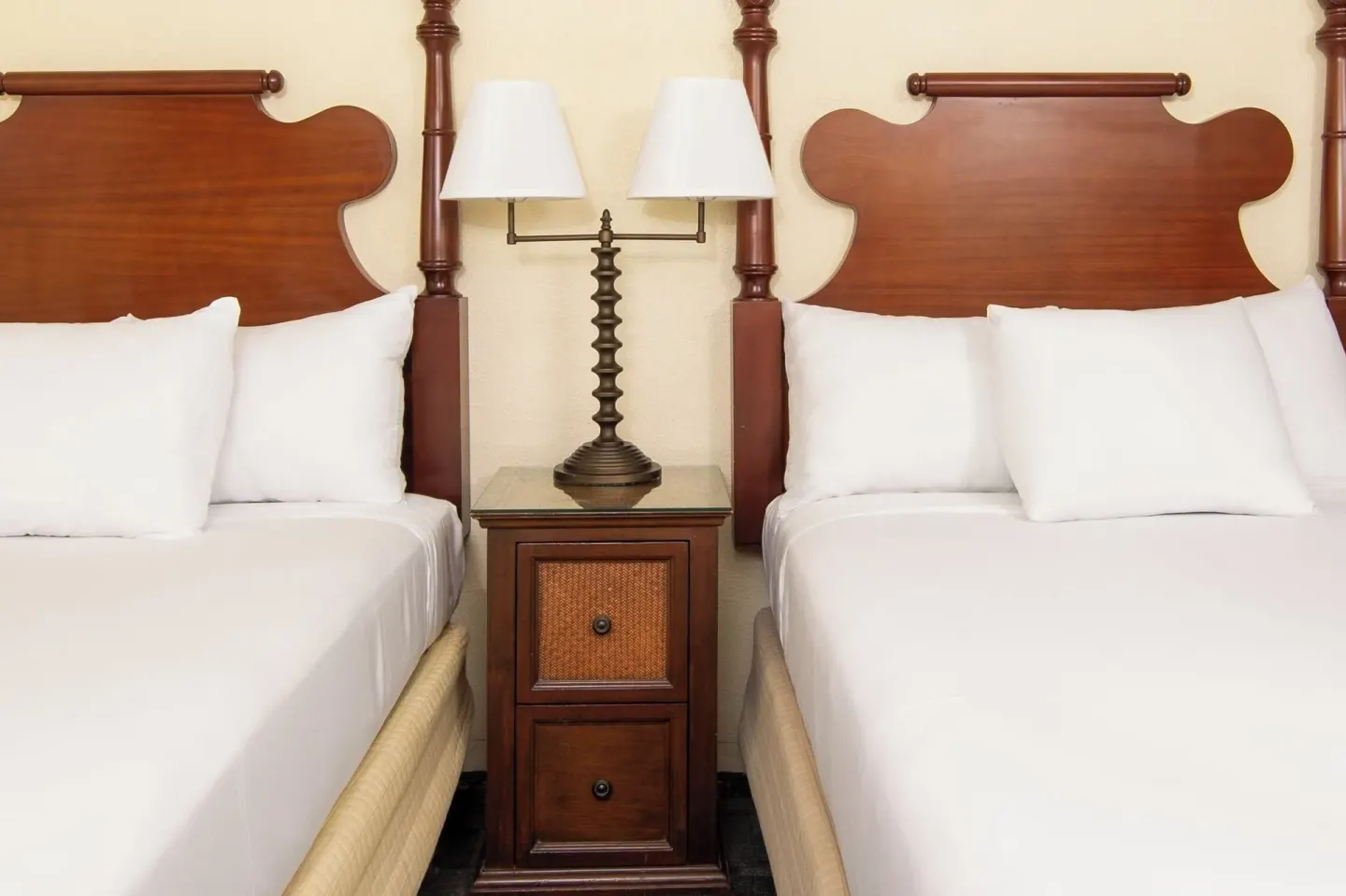 Two beds with wood headboards and a shared nightstand at Ohia Waikiki Studio Suites.