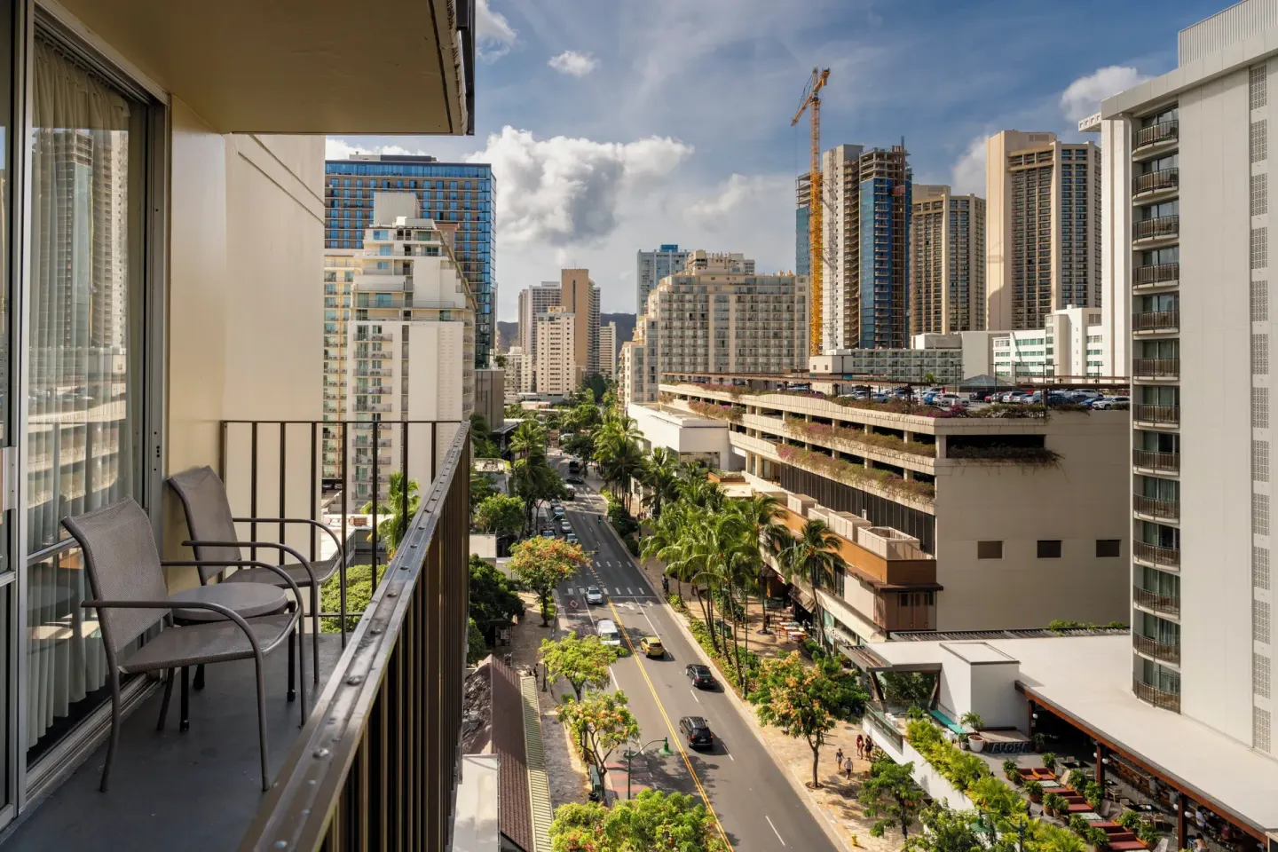 High-floor balcony with chairs and Waikiki city views at Ohia Waikiki Studio Suites.