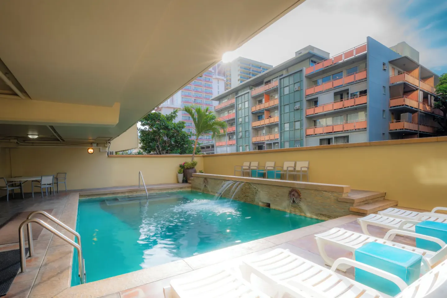 Pool deck with lounge chairs and city buildings at Ohia Waikiki Studio Suites.