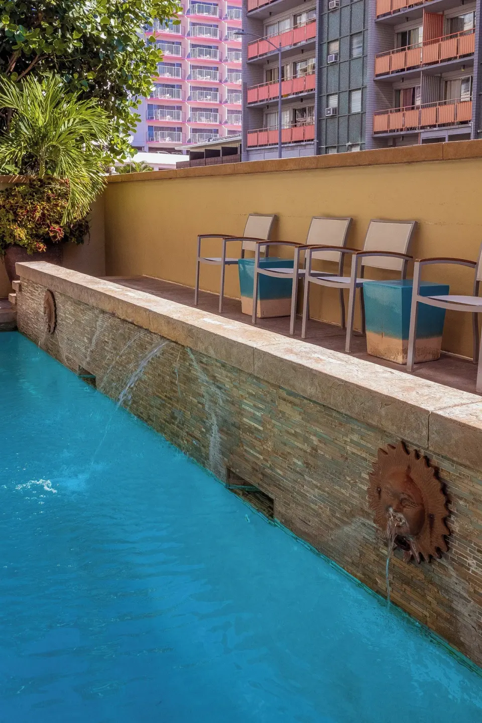 Poolside ledge with chairs and water features at Ohia Waikiki Studio Suites.