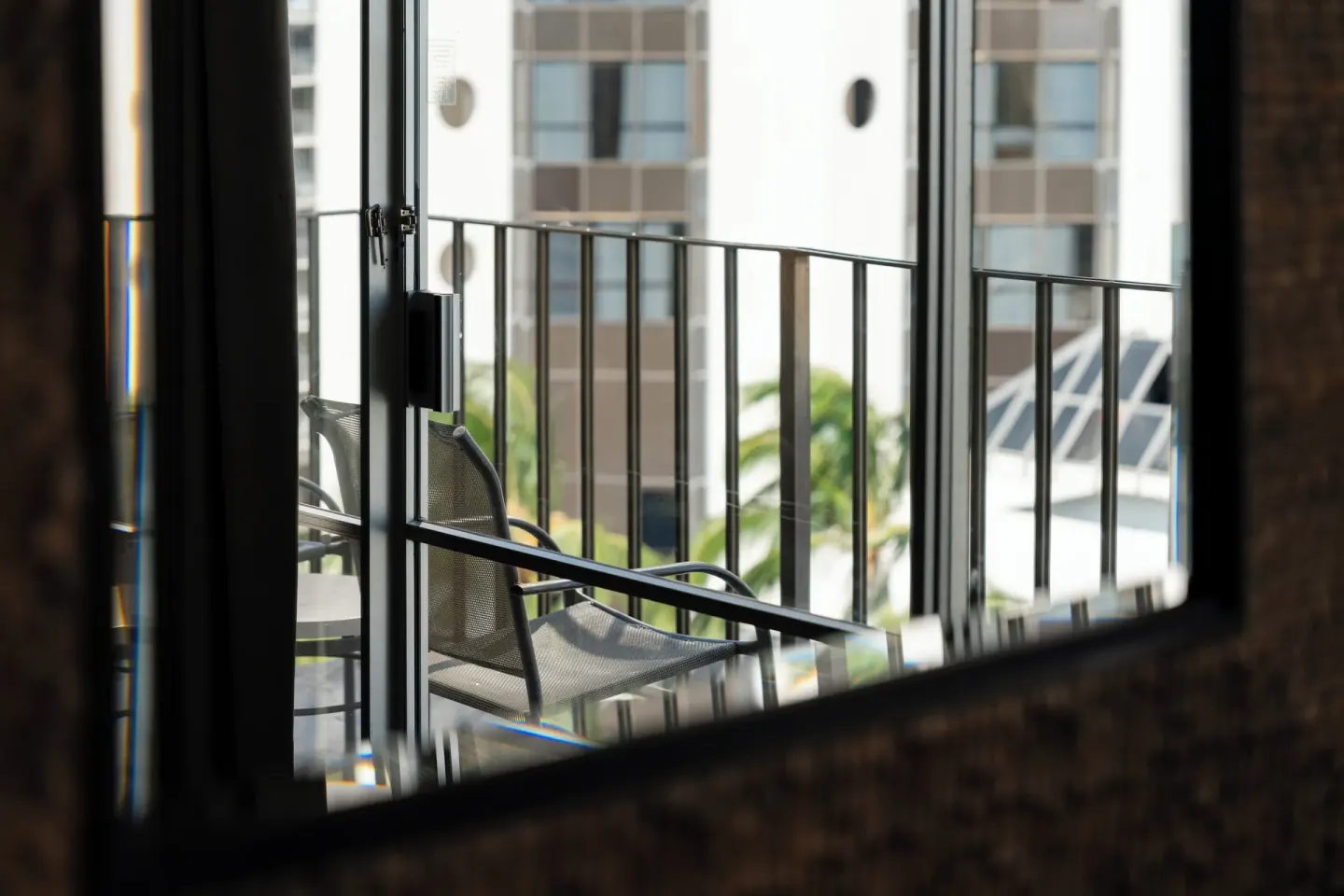 Balcony chair seen through a guest room mirror at Ohia Waikiki Studio Suites.