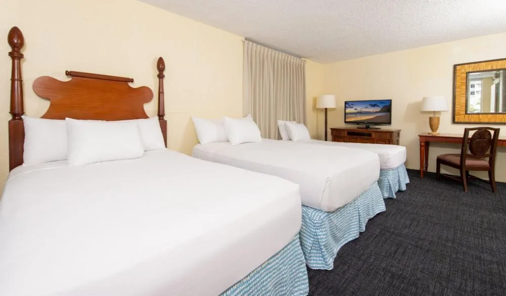 City View Studio Suite with three beds at Ohia Waikiki Studio Suites, plus TV, desk, mirror, and lamps.
