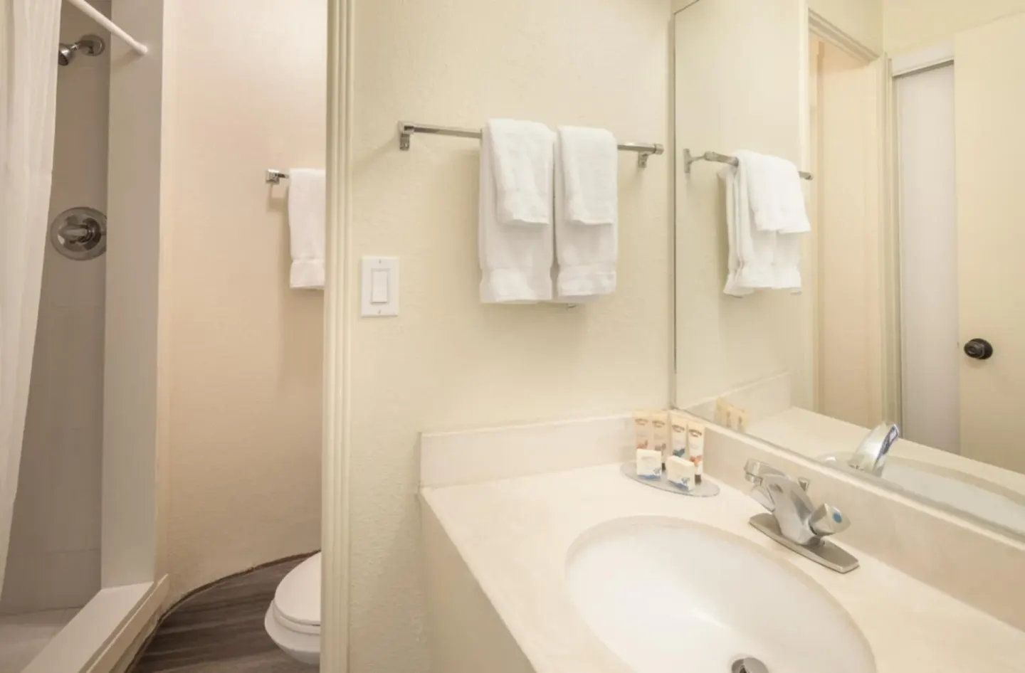 Bathroom with sink, mirror, towels, and shower at Ohia Waikiki Studio Suites.