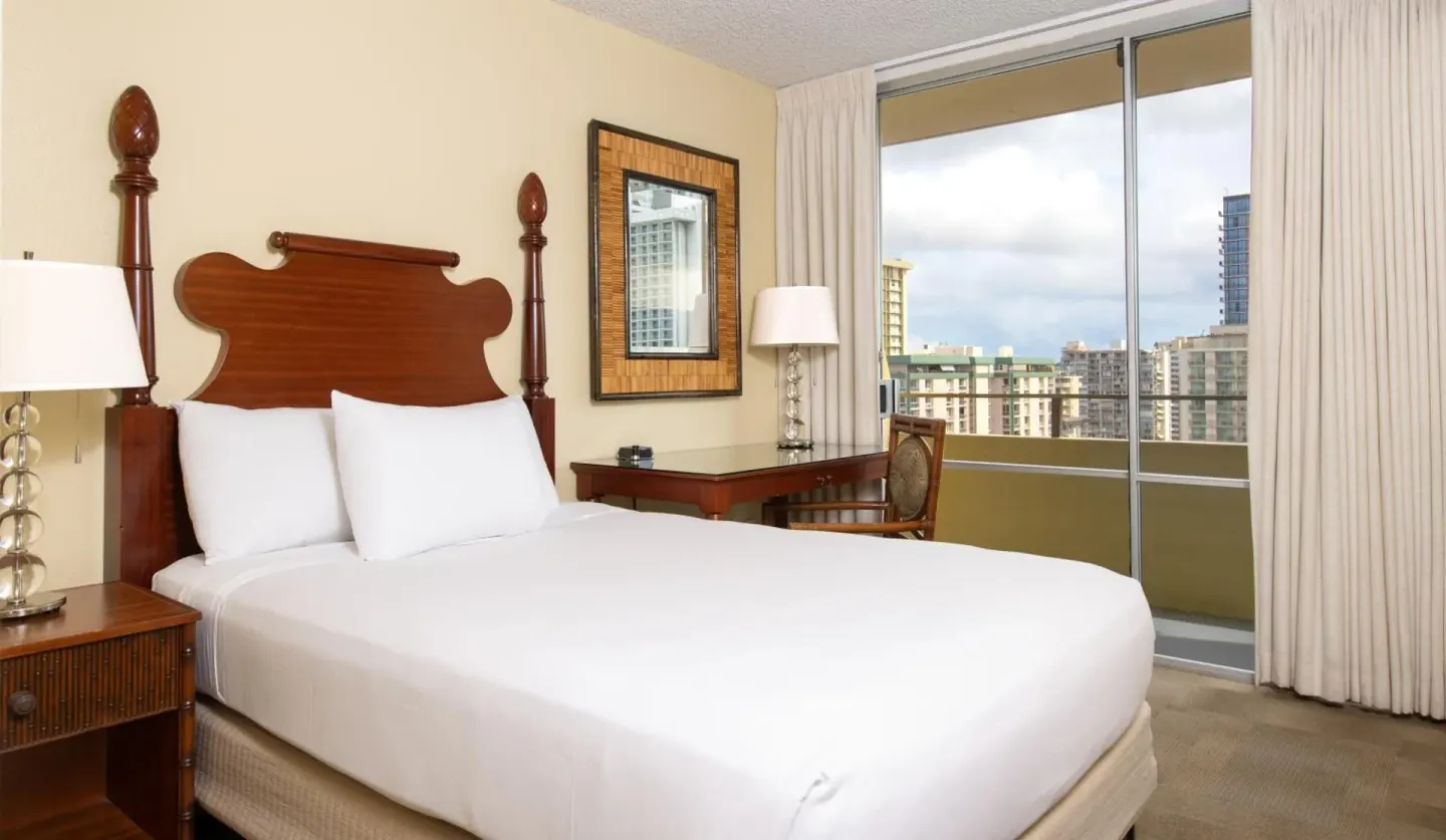 SKY View room with king bed, desk, and balcony windows at Ohia Waikiki Studio Suites.