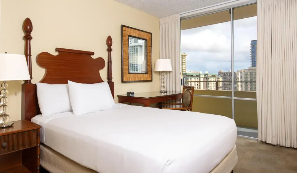 SKY View room with king bed, desk, and balcony windows at Ohia Waikiki Studio Suites.