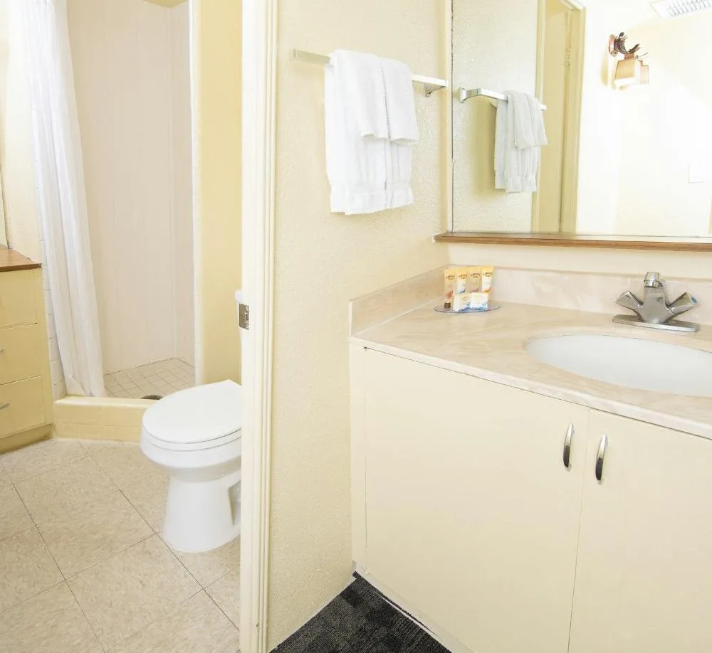 Bathroom vanity, toilet, and shower in a Sky View Junior Suite at Ohia Waikiki Studio Suites.