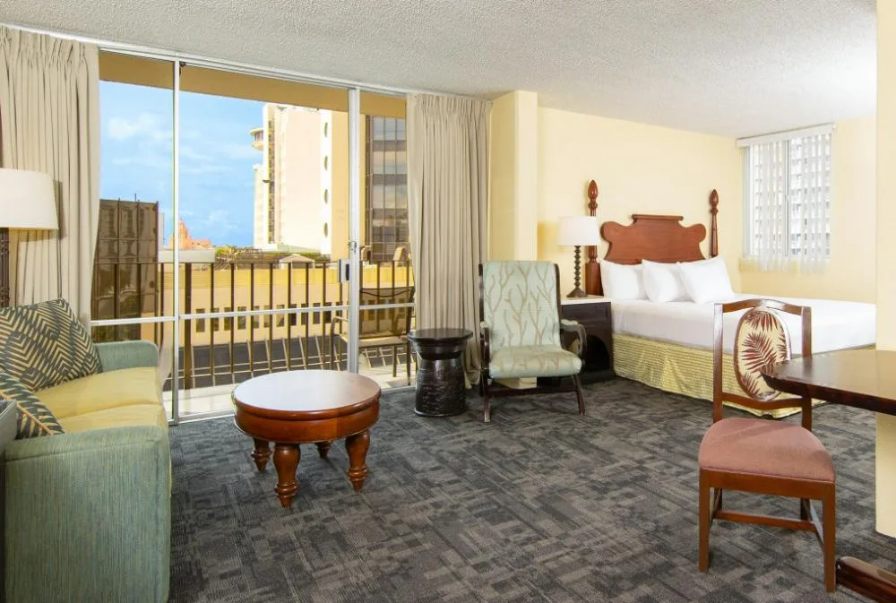 Sky View Junior Suite with bed, sofa, dining table, and balcony at Ohia Waikiki Studio Suites.