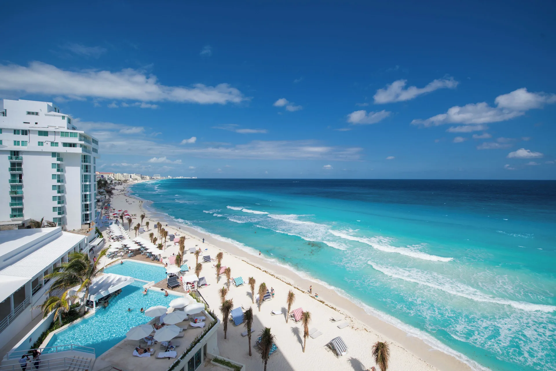 High view of the beach, pool, and Caribbean Sea at Oleo Cancun Playa Resort.