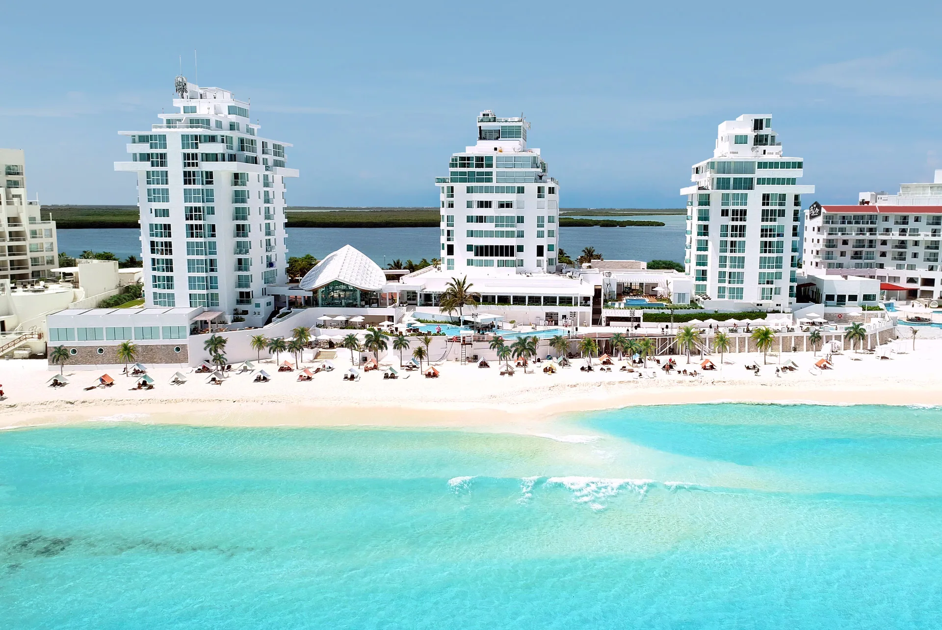 Aerial view of the beachfront towers and turquoise water at Oleo Cancun Playa Resort.