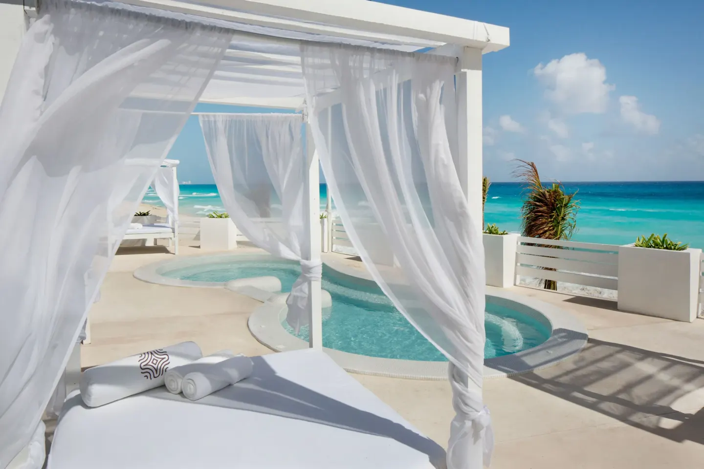 White cabana and small soaking pools overlooking the beach at Oleo Cancun Playa Resort.