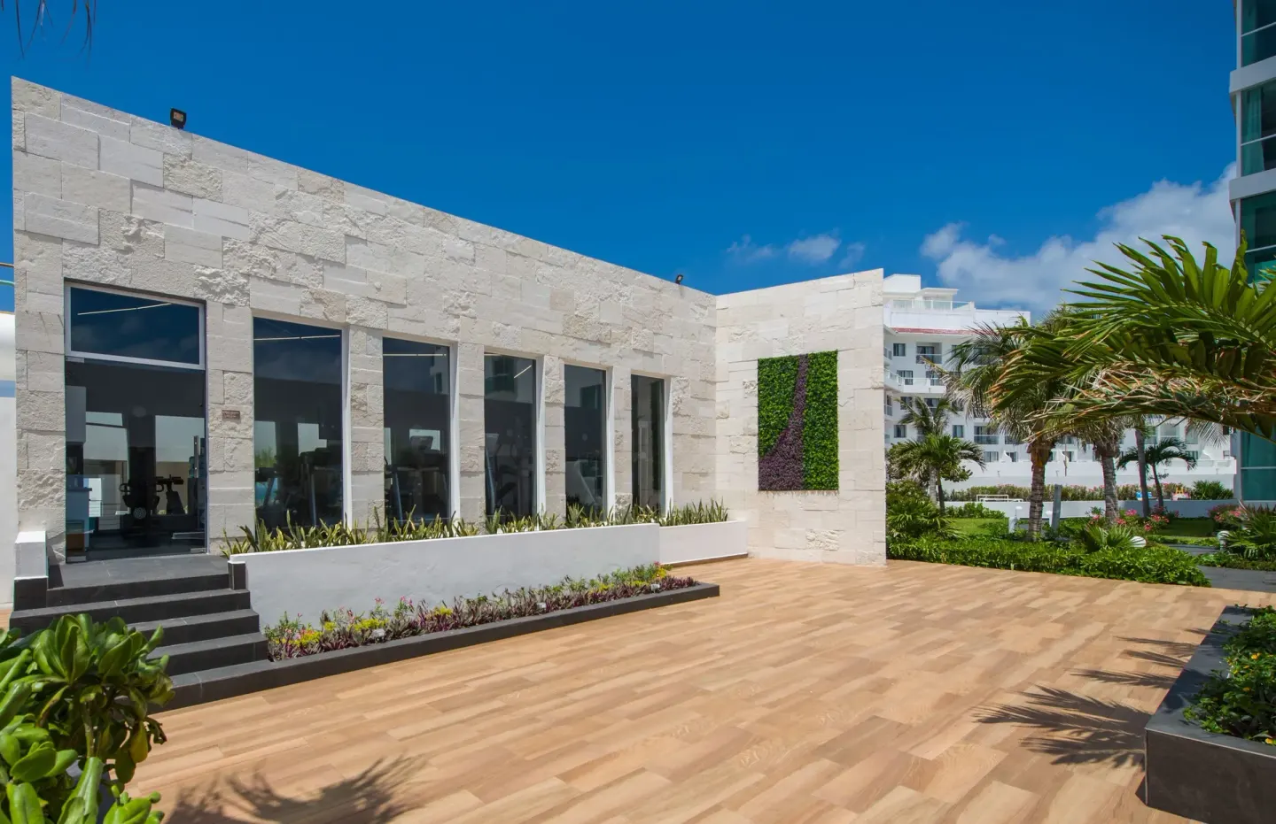 Stone-front fitness building and landscaped terrace at Oleo Cancun Playa Resort.