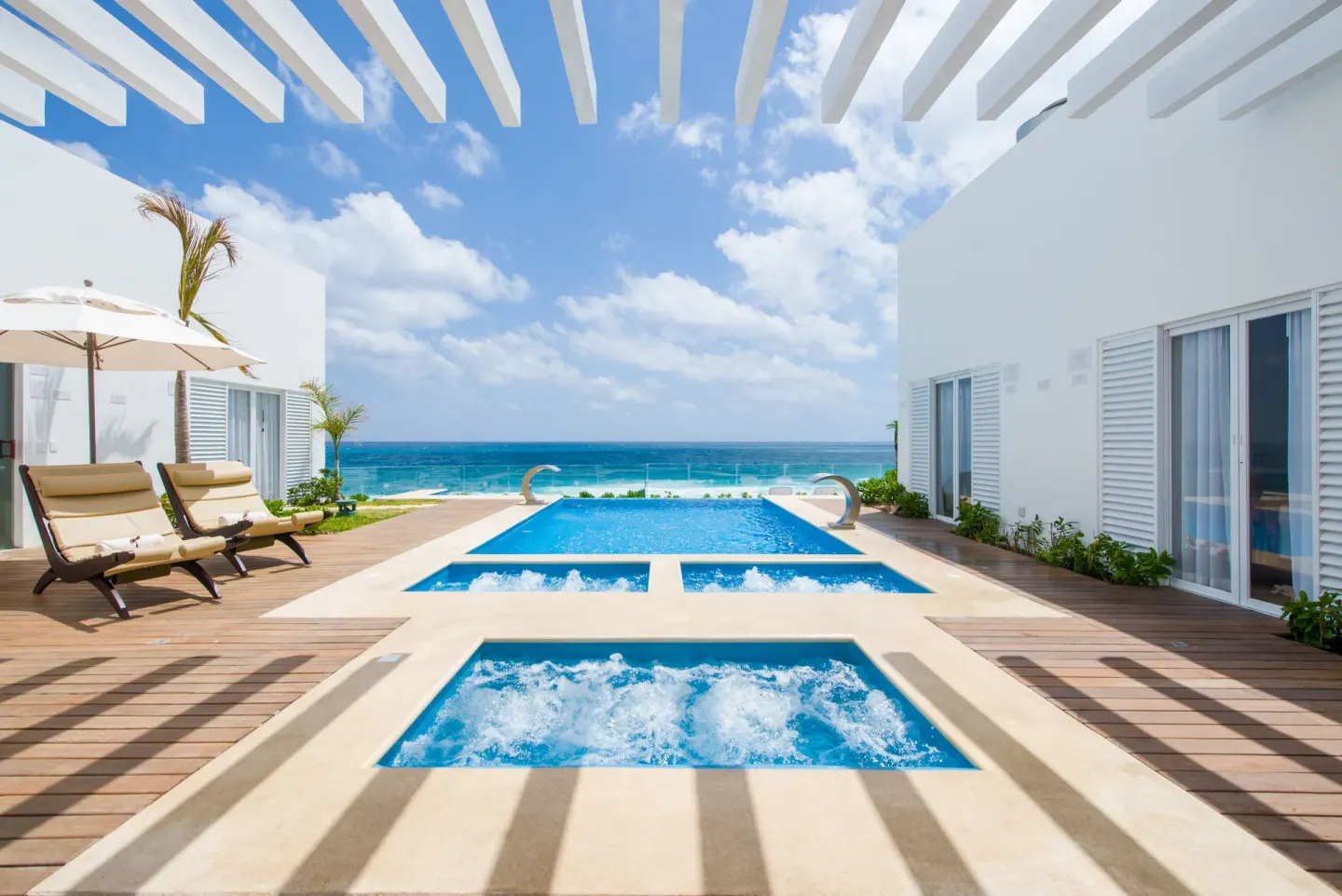 Oceanfront plunge pools and loungers at Oleo Cancun Playa Resort under a white pergola.