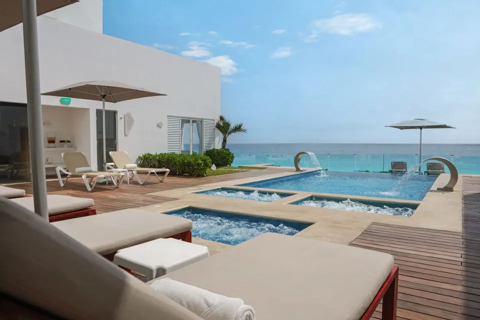 Oceanfront pool deck with bubbling spa pools at Oleo Cancun Playa Resort.