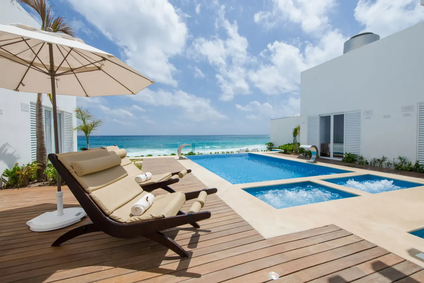 Pool terrace with loungers, umbrella, and ocean view at Oleo Cancun Playa Resort.