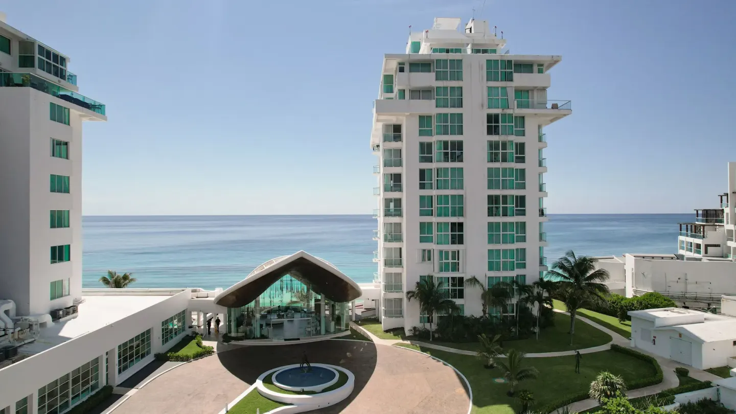 Resort towers, entrance canopy and ocean backdrop at Oleo Cancun Playa Resort.