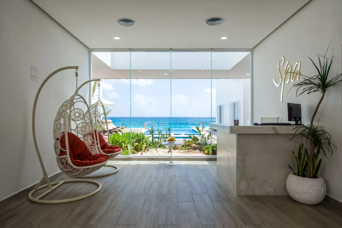 Spa reception with hanging chairs and ocean view at Oleo Cancun Playa Resort.