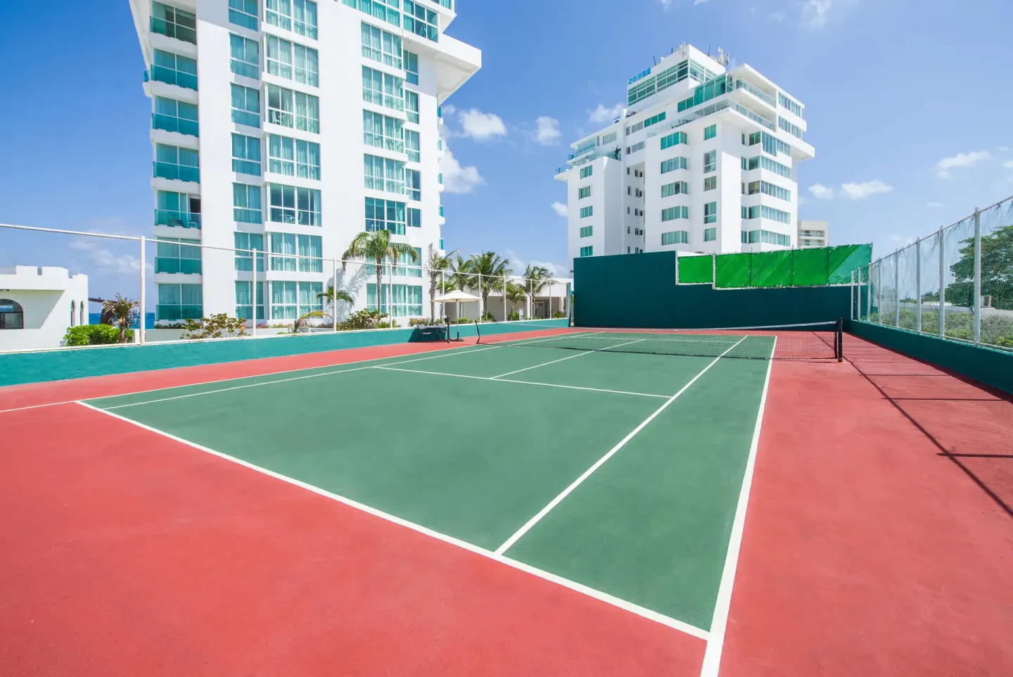 Outdoor tennis court between resort towers at Oleo Cancun Playa Resort.