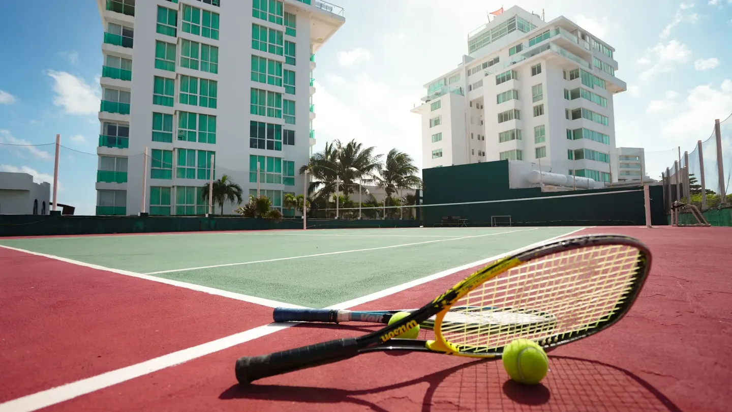 Tennis rackets and a ball on the court at Oleo Cancun Playa Resort.
