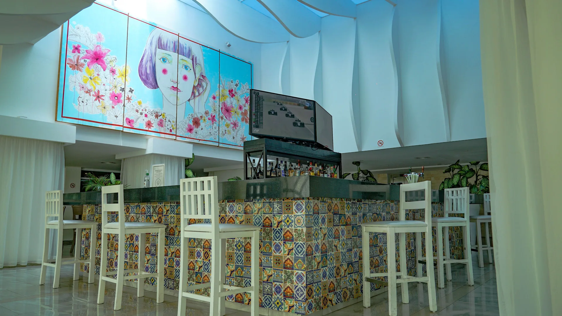 Lobby bar with patterned tile counter and high chairs at Oleo Cancun Playa Resort.