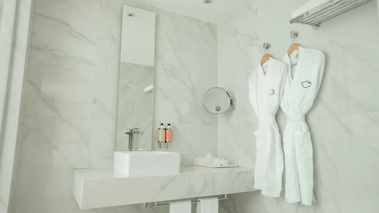 Inspira Junior Suite bathroom vanity with robes at Oleo Cancun Playa Resort.