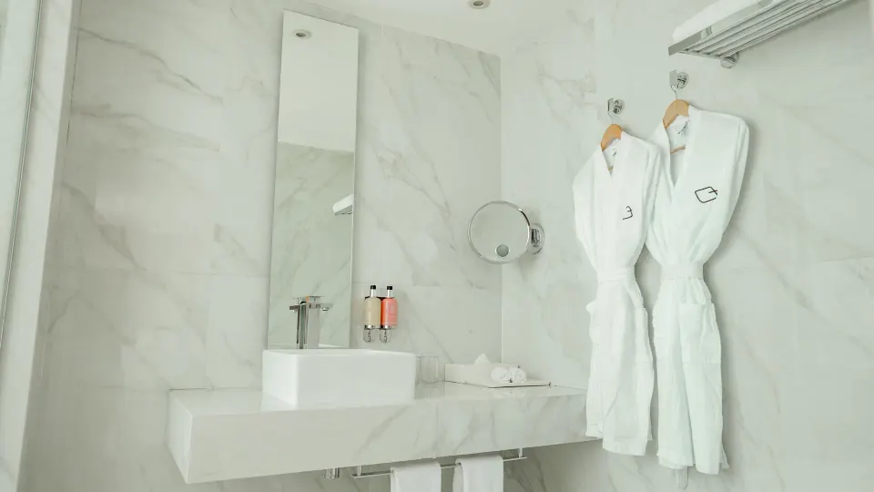 Inspira Junior Suite bathroom vanity with robes at Oleo Cancun Playa Resort.