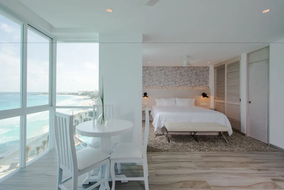 Inspira Junior Suite king bed beside a corner ocean view at Oleo Cancun Playa Resort.