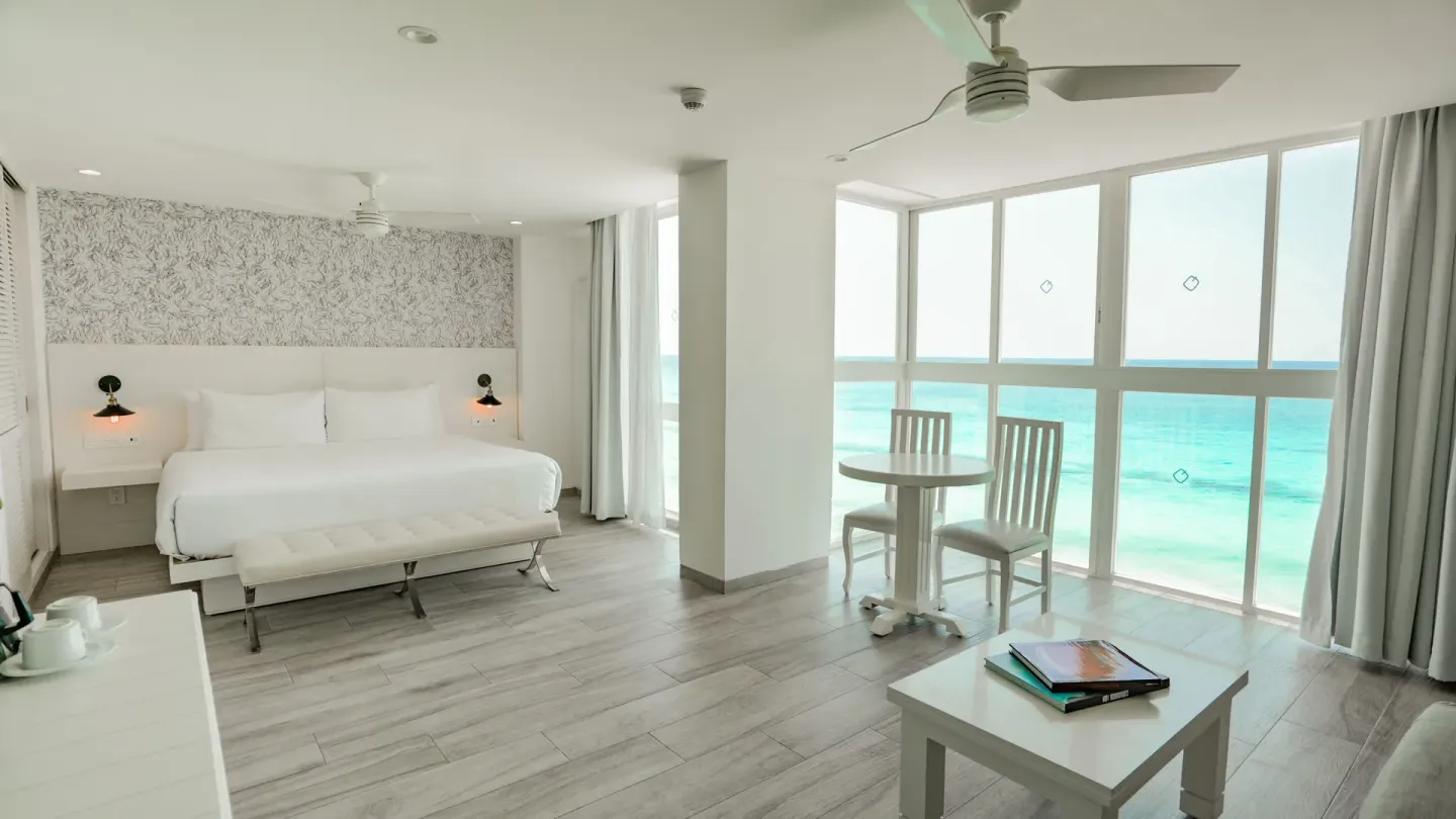 Inspira Junior Suite king bed and ocean-facing dining nook at Oleo Cancun Playa Resort.