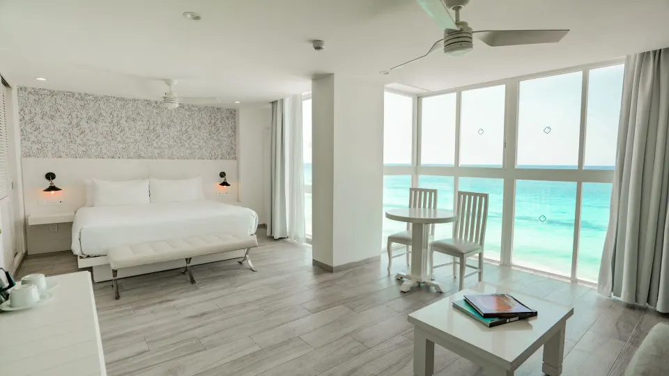 Inspira Junior Suite king bed and ocean-facing dining nook at Oleo Cancun Playa Resort.