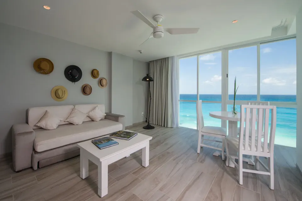 Inspira Junior Suite sitting area with oceanfront windows at Oleo Cancun Playa Resort.