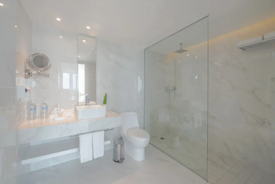 Junior Suite Sunset bathroom with glass shower and white vanity at Oleo Cancun Playa Resort.