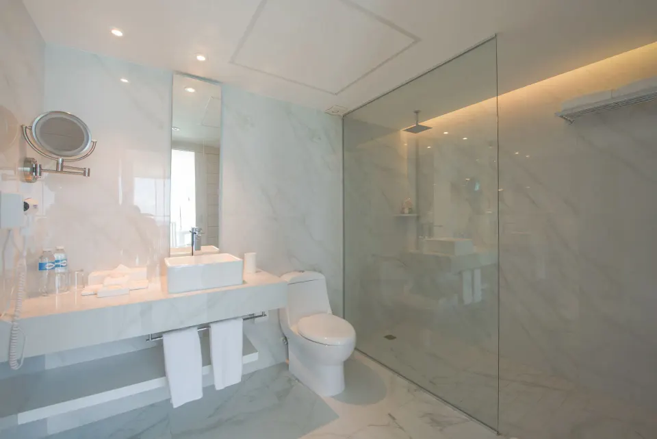 Standard Room bathroom with vanity, toilet and glass shower at Oleo Cancun Playa Resort.