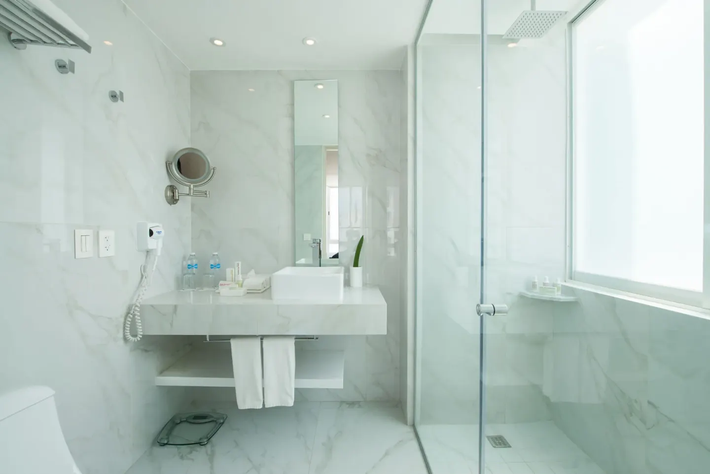Standard Room bathroom with vanity and walk-in shower by a frosted window at Oleo Cancun Playa Resort.