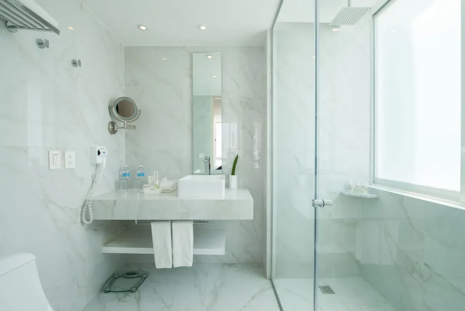 Standard Room bathroom with vanity and walk-in shower by a frosted window at Oleo Cancun Playa Resort.