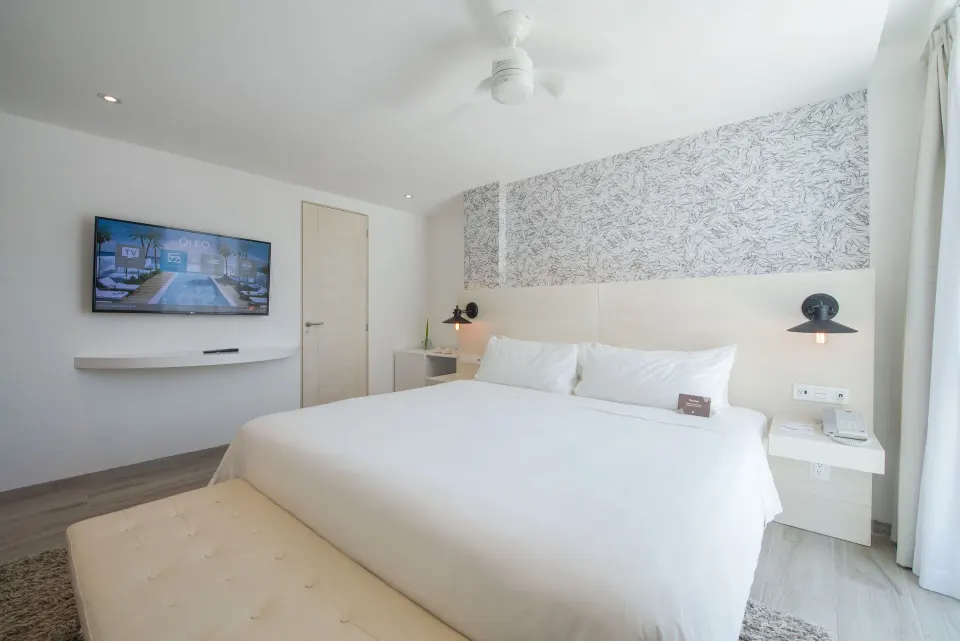 Standard Room king bed with wall-mounted TV at Oleo Cancun Playa Resort.