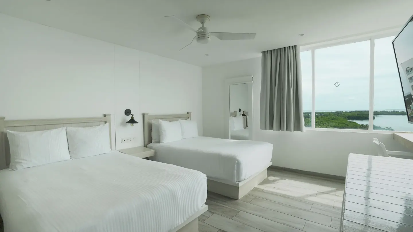 Standard Room with two beds and lagoon-facing window at Oleo Cancun Playa Resort.