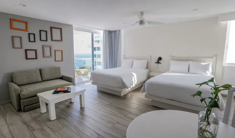 Superior Sunset room with two double beds and partial ocean view at Oleo Cancun Playa Resort.