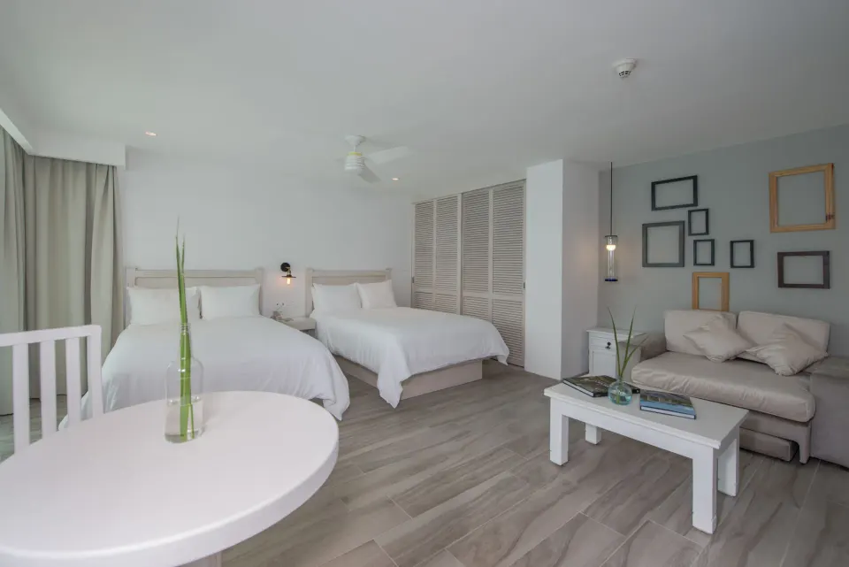 Superior Sunset room with two double beds, sofa, and round table at Oleo Cancun Playa Resort.