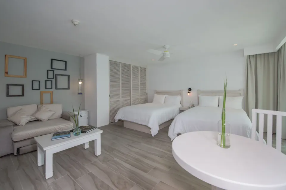 Superior Sunset room with two double beds and sitting area at Oleo Cancun Playa Resort.