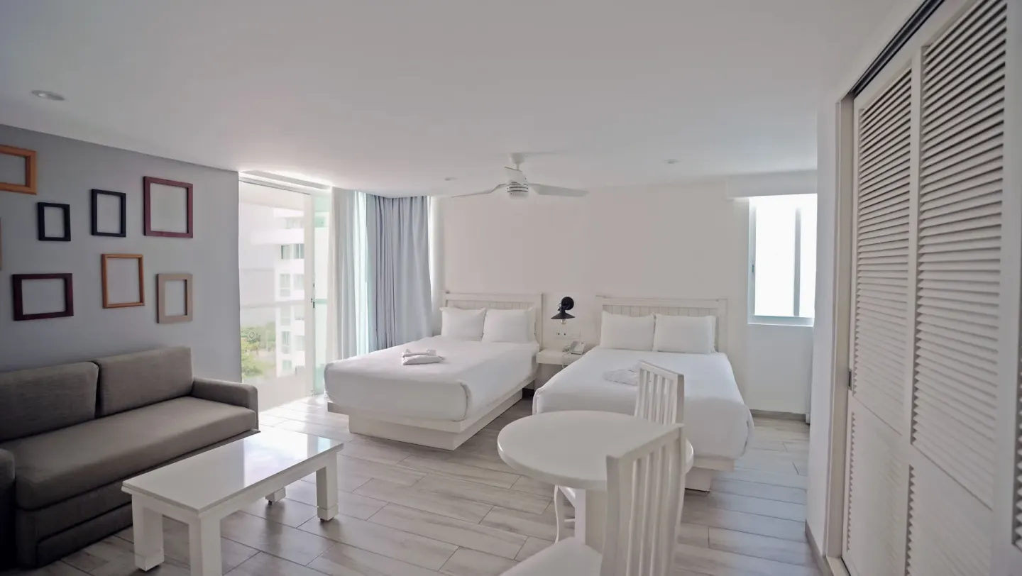 Superior Sunset room with two double beds, sofa, and dining table at Oleo Cancun Playa Resort.
