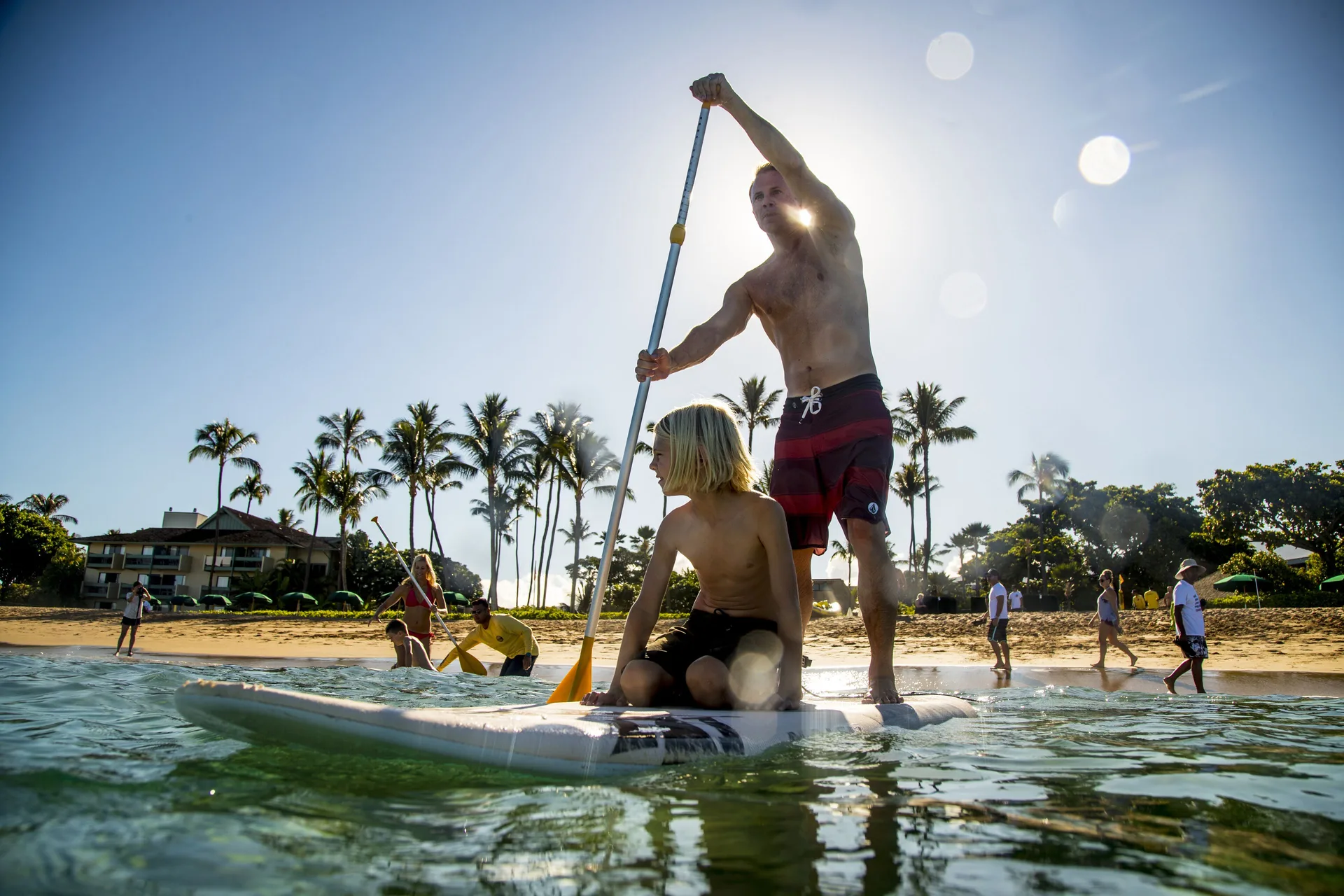 Adult and child paddleboarding off the beach at Outrigger Kaanapali Beach Resort.